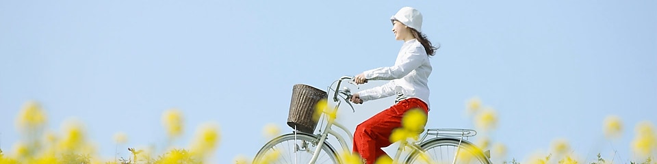 A young woman rides a bicycle through a summer field